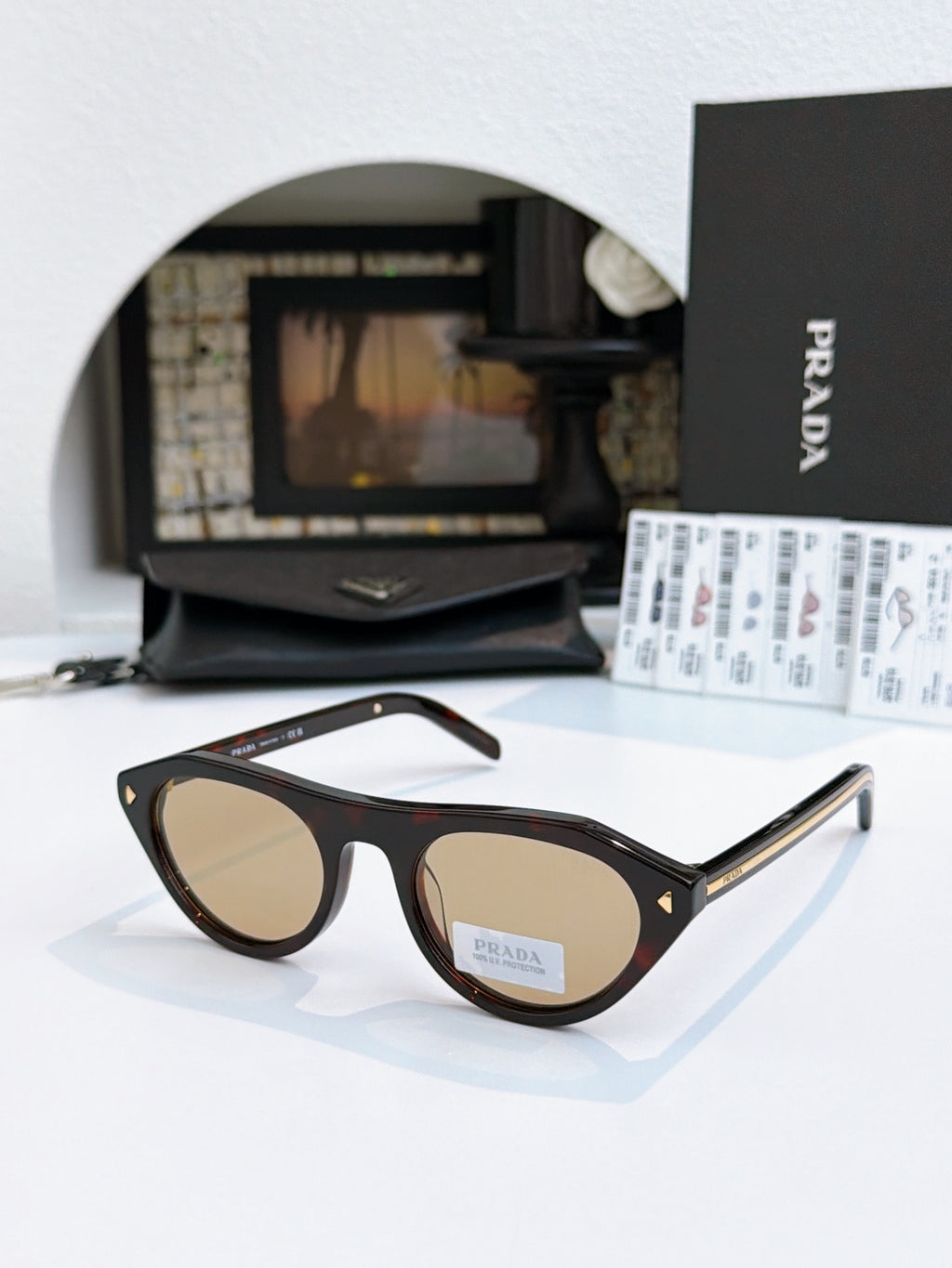 Prada sunglasses with black acetate frames and tan lenses, metal temple tips.