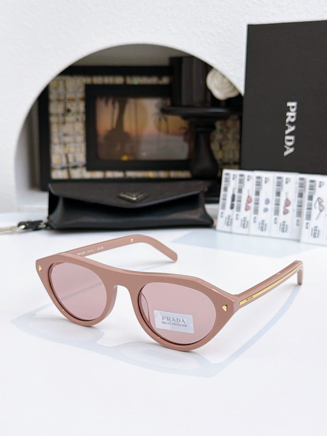 Prada sunglasses with tortoiseshell acetate frames and pink-tinted lenses, minimal metal detail.