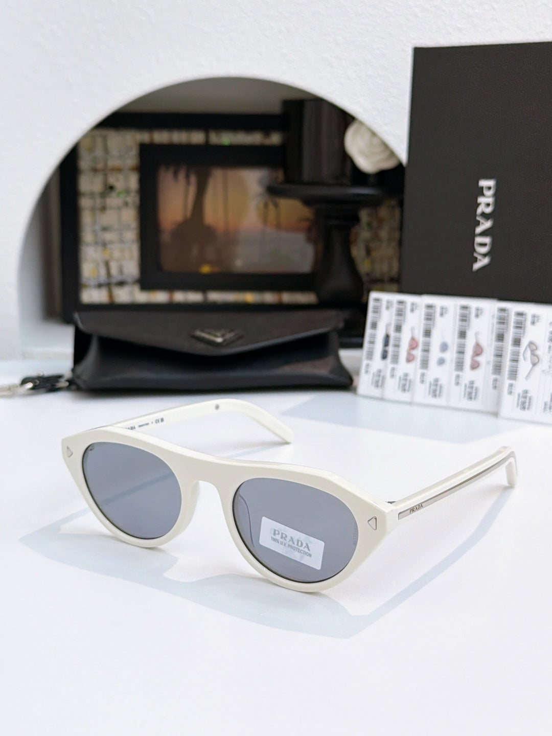 Prada sunglasses with white acetate frames and dark lenses, metal temple tips.