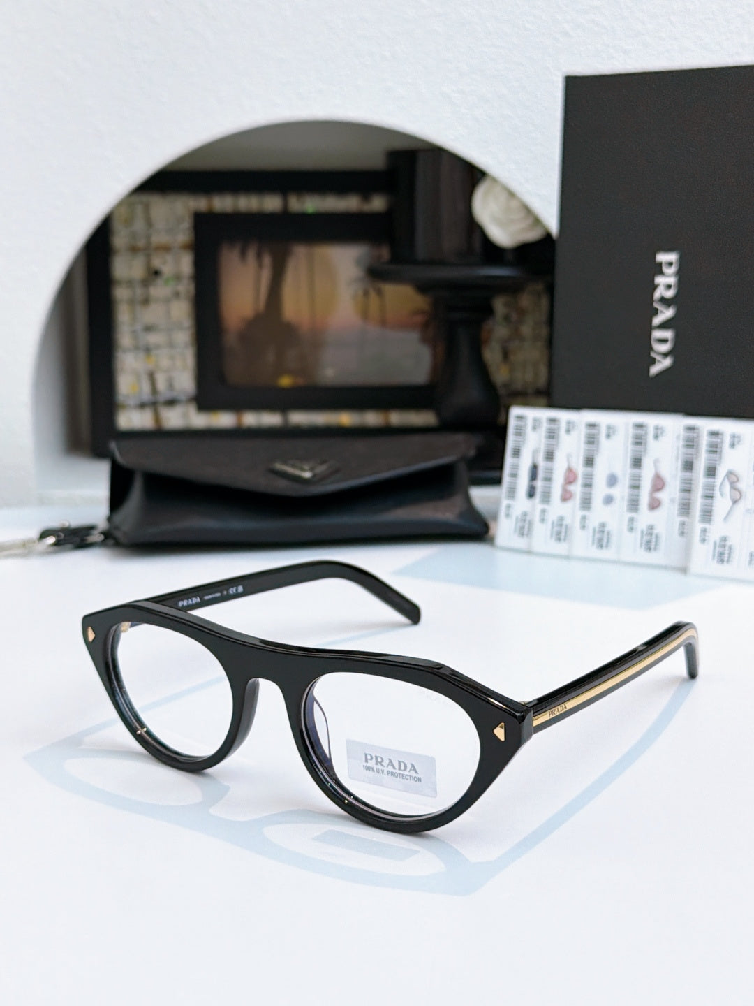Prada sunglasses with black acetate frames and light tan lenses, gold-trim temple detail.