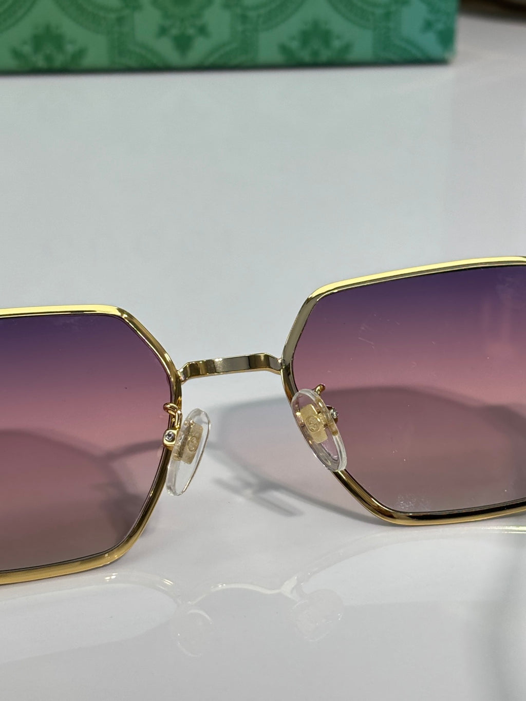 Gucci hexagon sunglasses close-up with purple gradient lenses and gold-tone frame