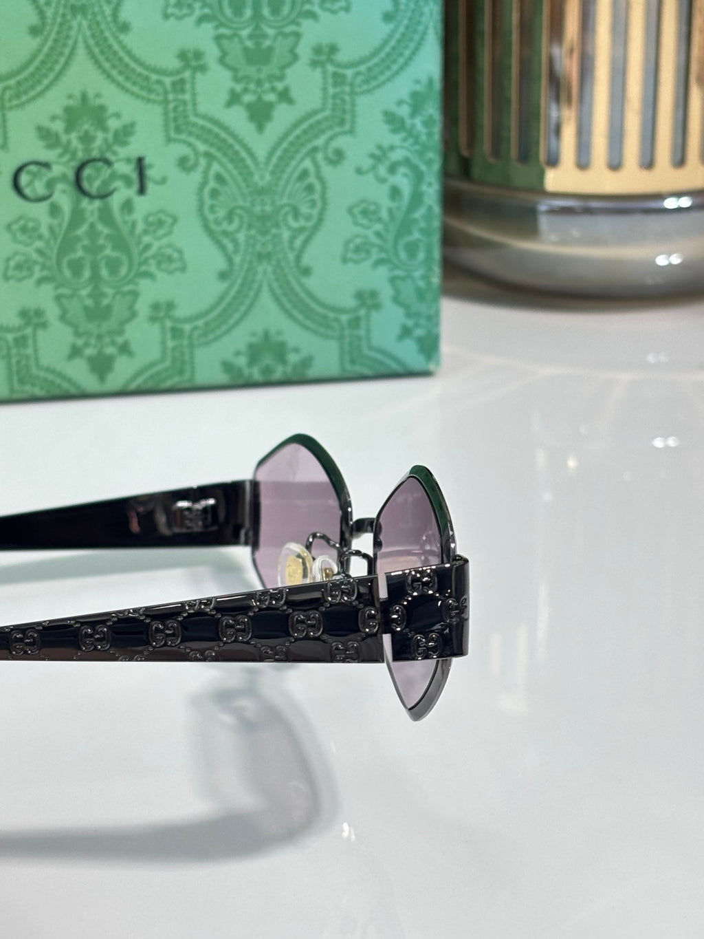 Cat-eye sunglasses side view with dark lenses, black temples, and ornate metal hinge.