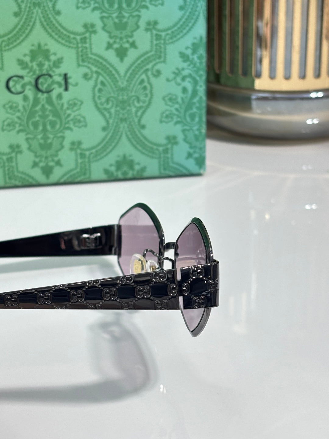 Cat-eye sunglasses side view with dark lenses, black temples, and ornate metal hinge.
