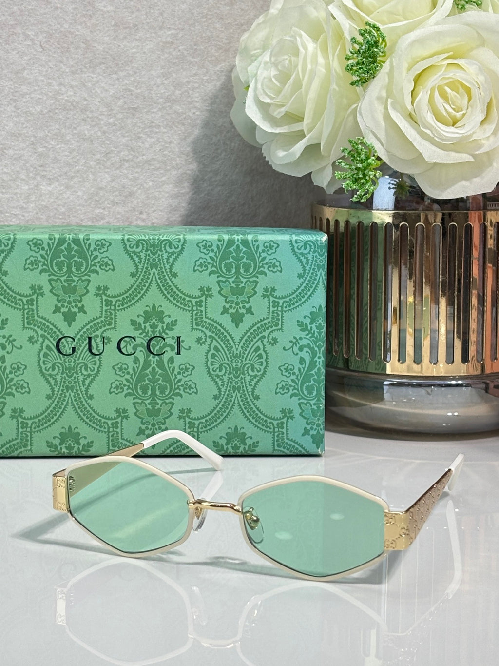 Cat-eye sunglasses with mint-green lenses, thin gold frame, and light metal temple tips.