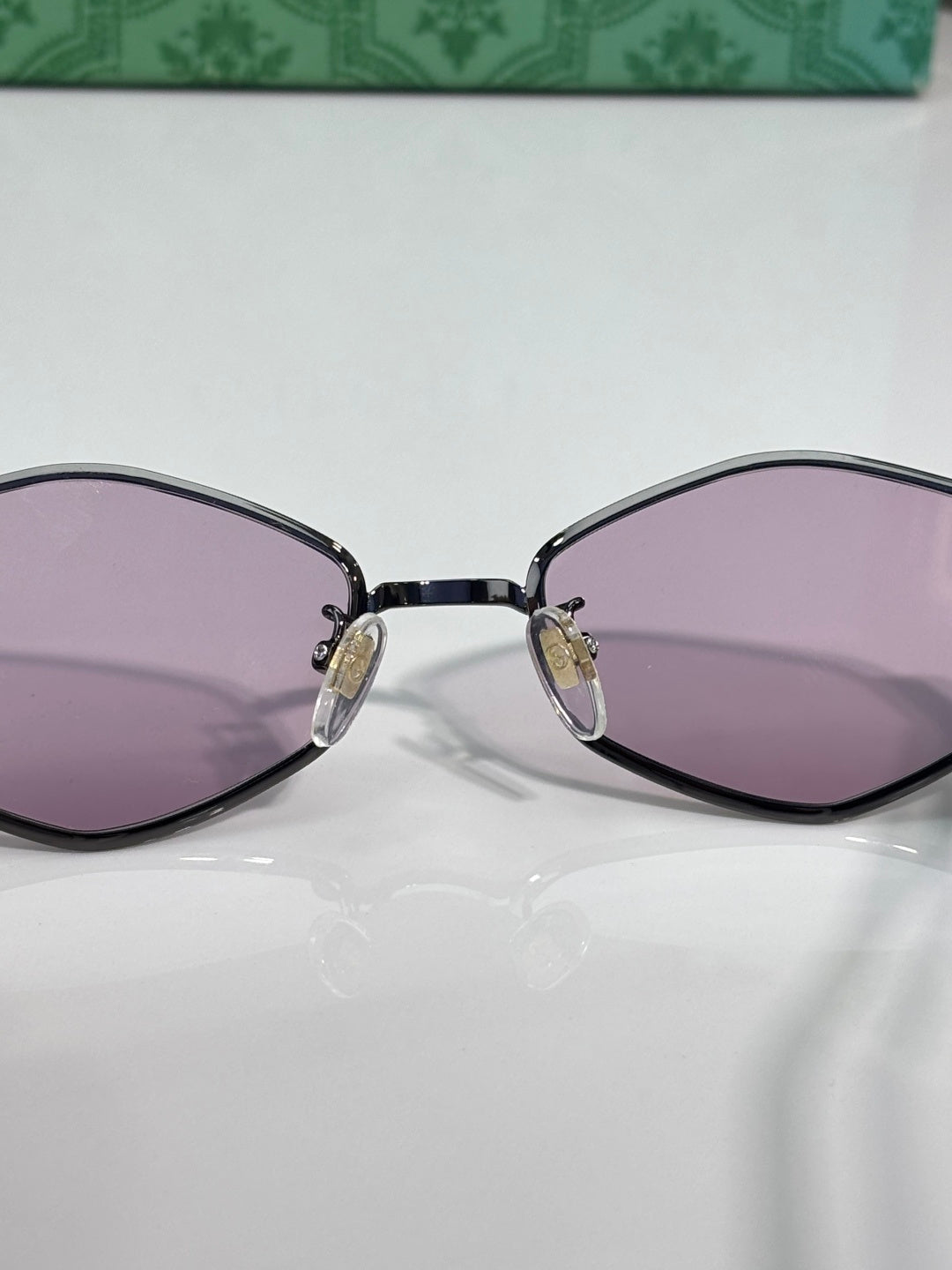 Cat-eye sunglasses close-up with dark frame and lavender-tinted lenses.