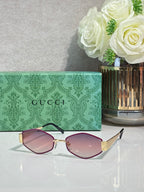 Cat-eye sunglasses with pink lenses, rose-gold frame, and gold temples with dark insets.