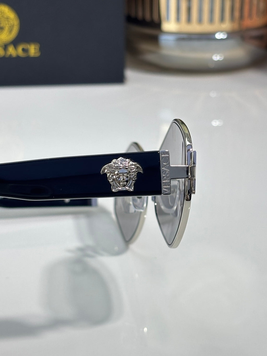 Versace sunglasses hinge close-up with engraved medallion on silver frame