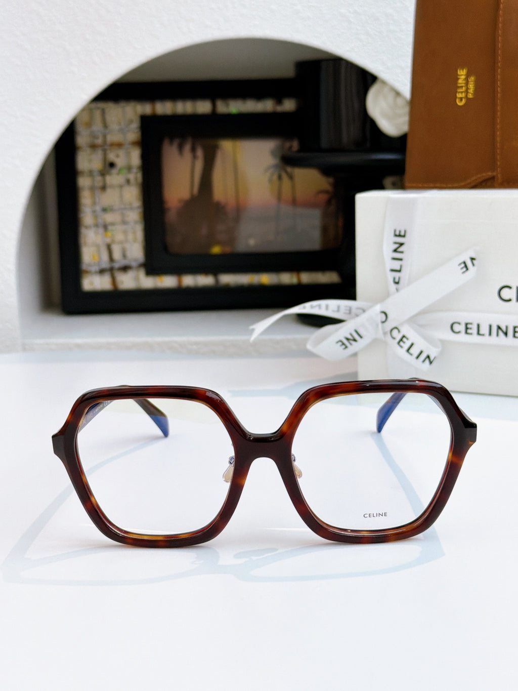Reddish tortoiseshell square eyeglasses with clear lenses and gold hinge detail.
