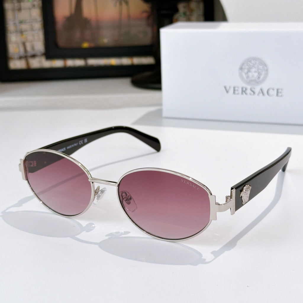 Sunglasses with gold frame, pink lenses, and black temple arms
