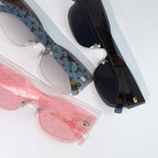 Louis Vuitton sunglasses close-up showing pink, white, and dark frames with gold-tone hardware.