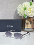 Chanel sunglasses with dark lenses, gold metal frame and chain detail