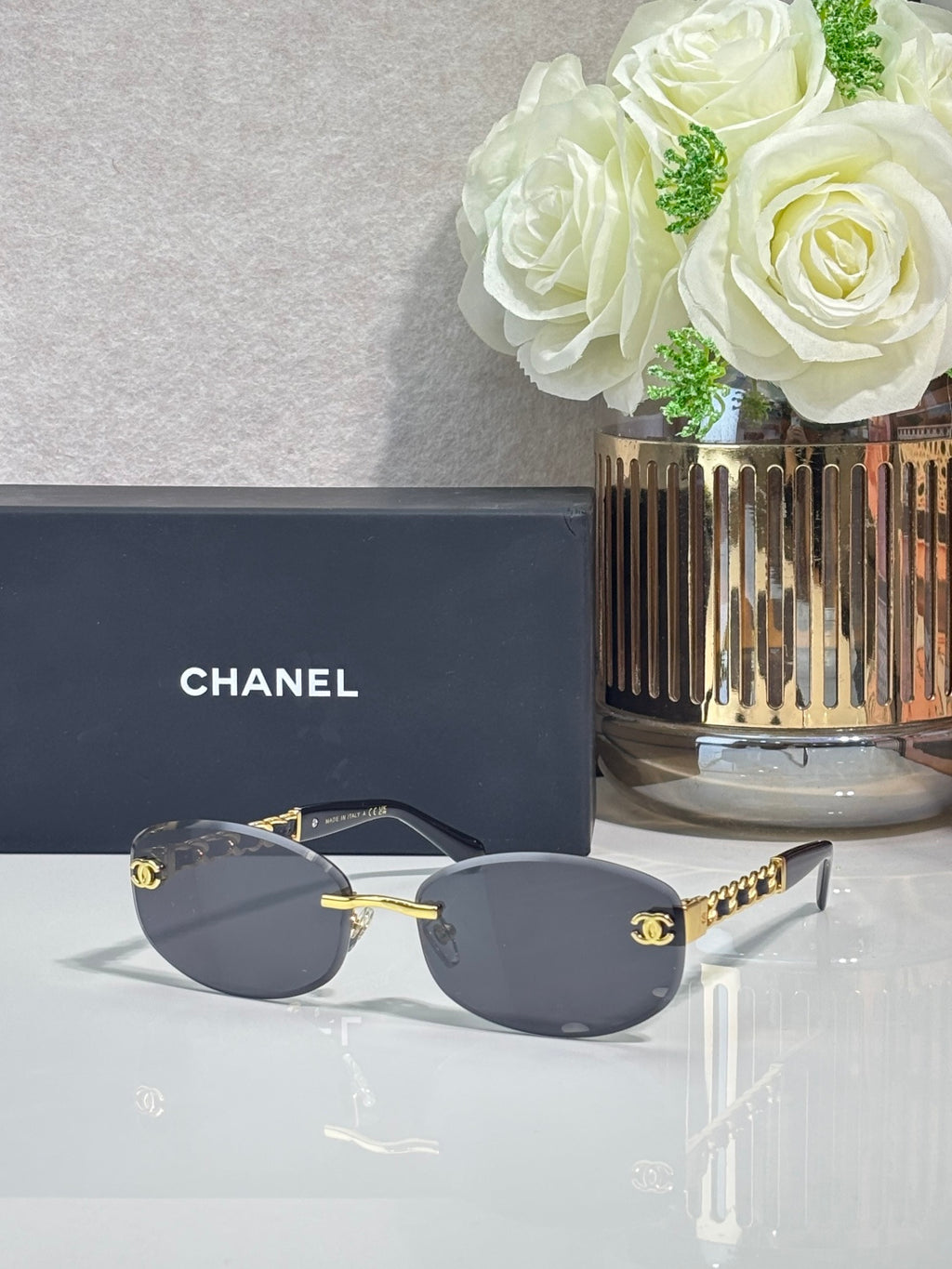 Chanel sunglasses with dark lenses, silver frame with gold accents