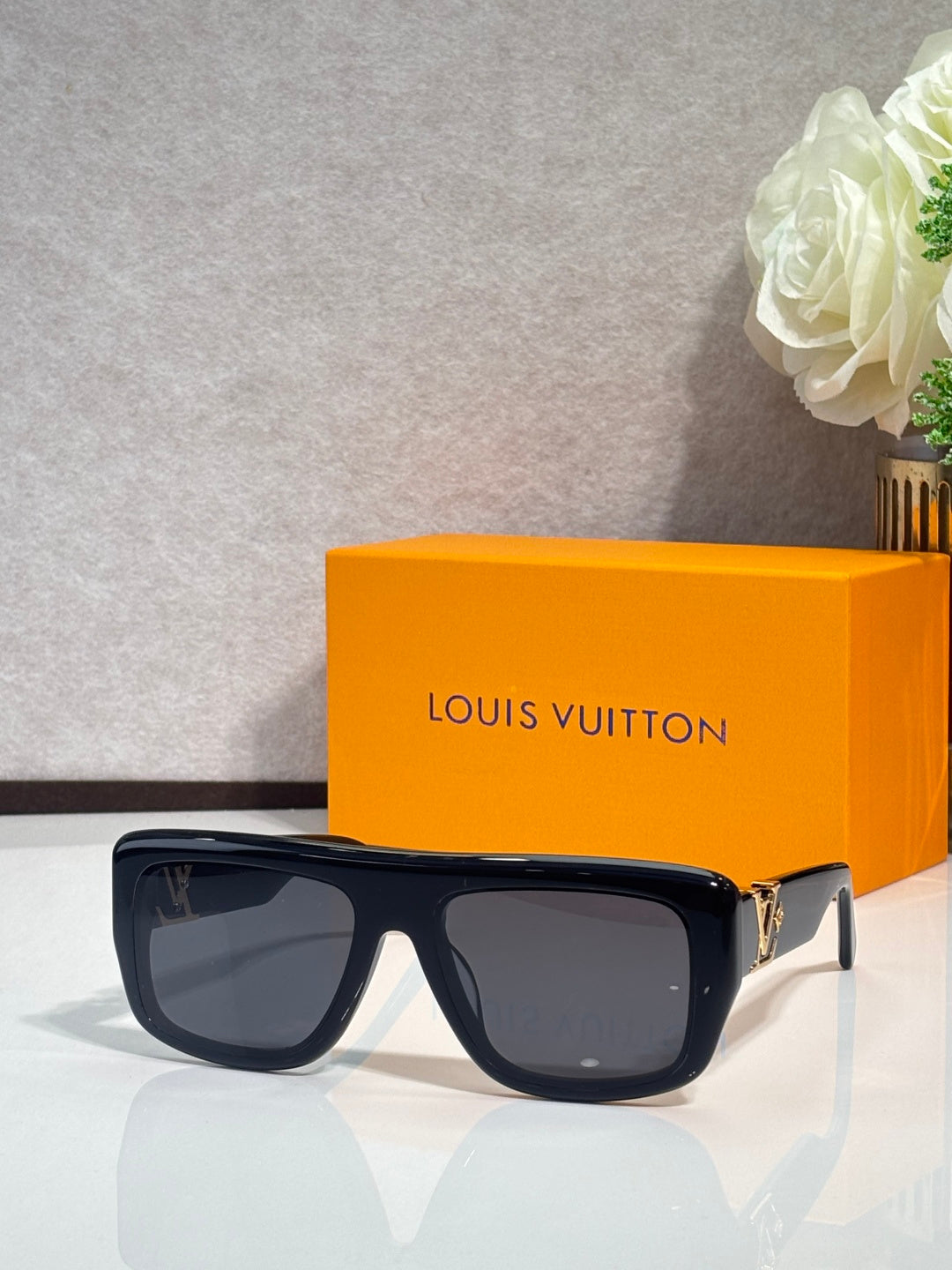 Black square sunglasses with tinted lenses and gold-tone logo on temples