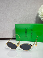 Gold oval sunglasses with dark lenses and curved metal arms