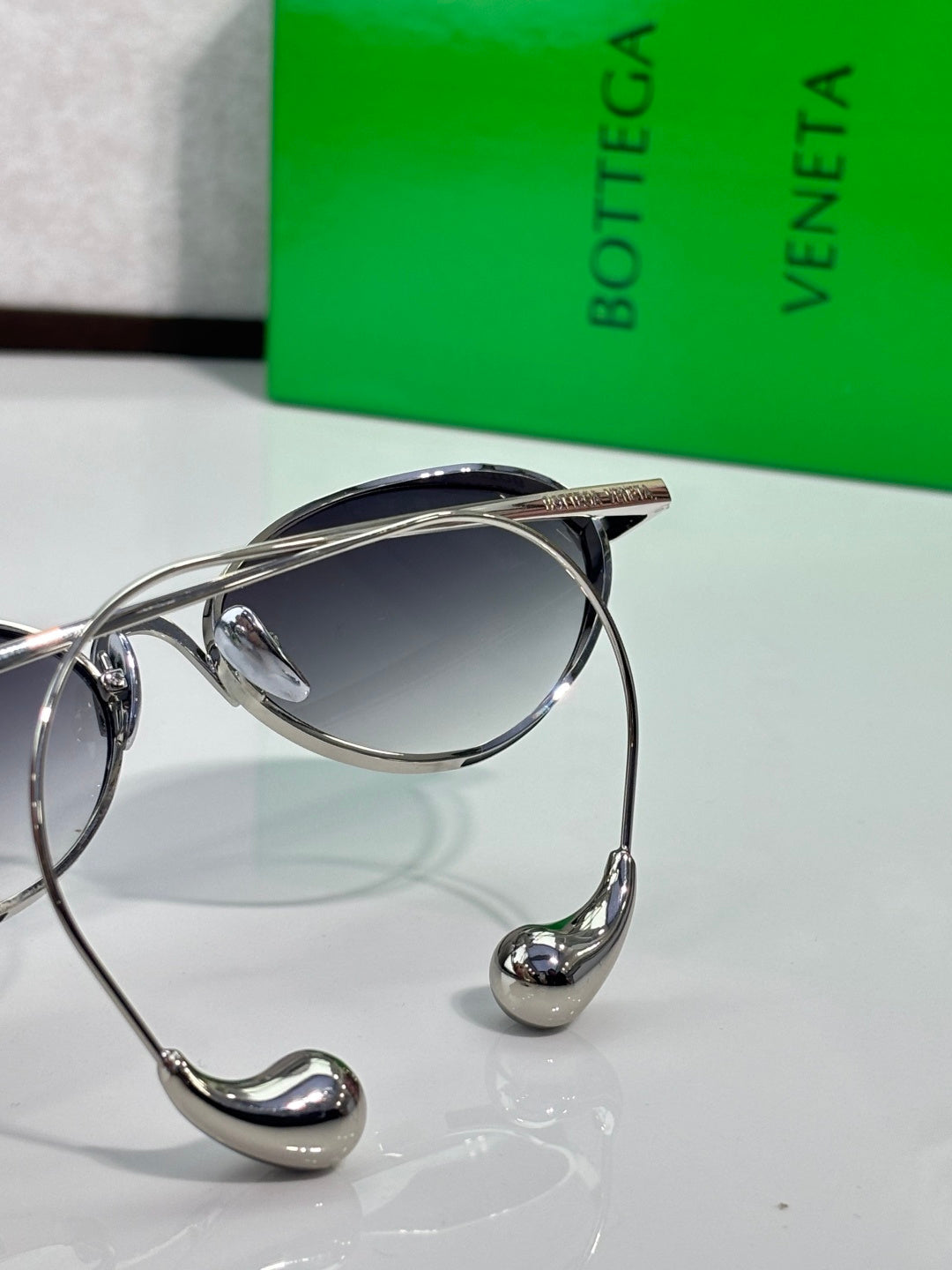 Silver oval sunglasses close-up with dark lenses and curved metal arms
