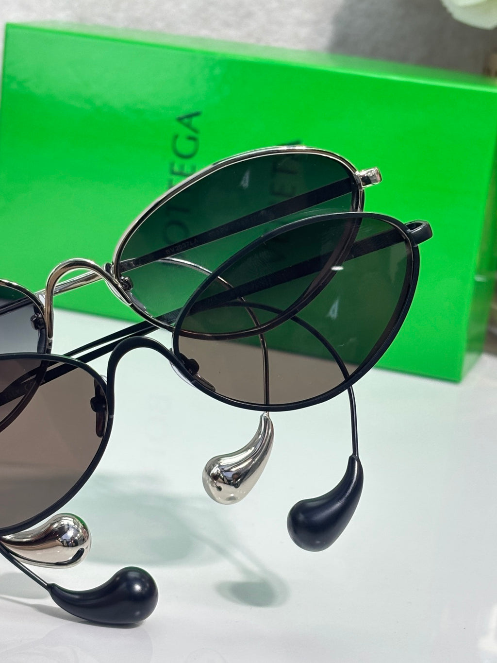 Round sunglasses close-up with dark lenses, silver bridge, and black arms