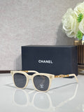 Sunglasses with cream frames, gold chain detail on temples, and dark lenses