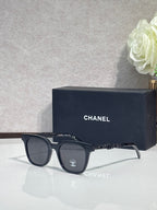 Sunglasses with black frames and dark lenses, with ornate temple detailing