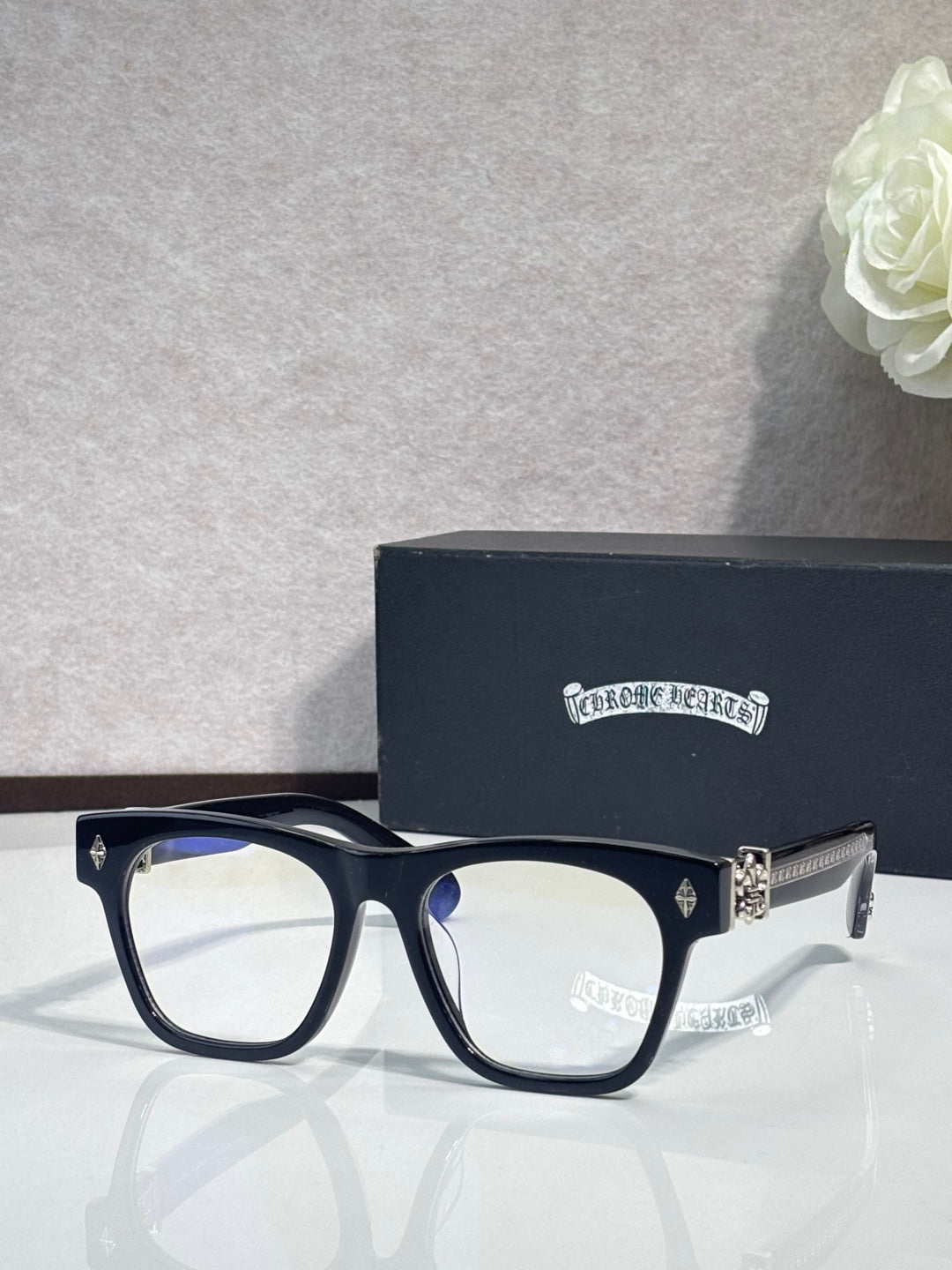 Chrome glasses with dark frames and blue-toned temple hinge with small emblem accents