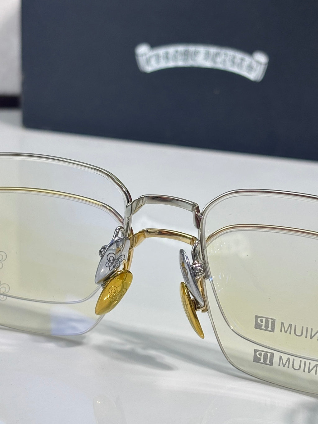Front view of gold and silver eyeglass frames with clear lenses and amber temple tips