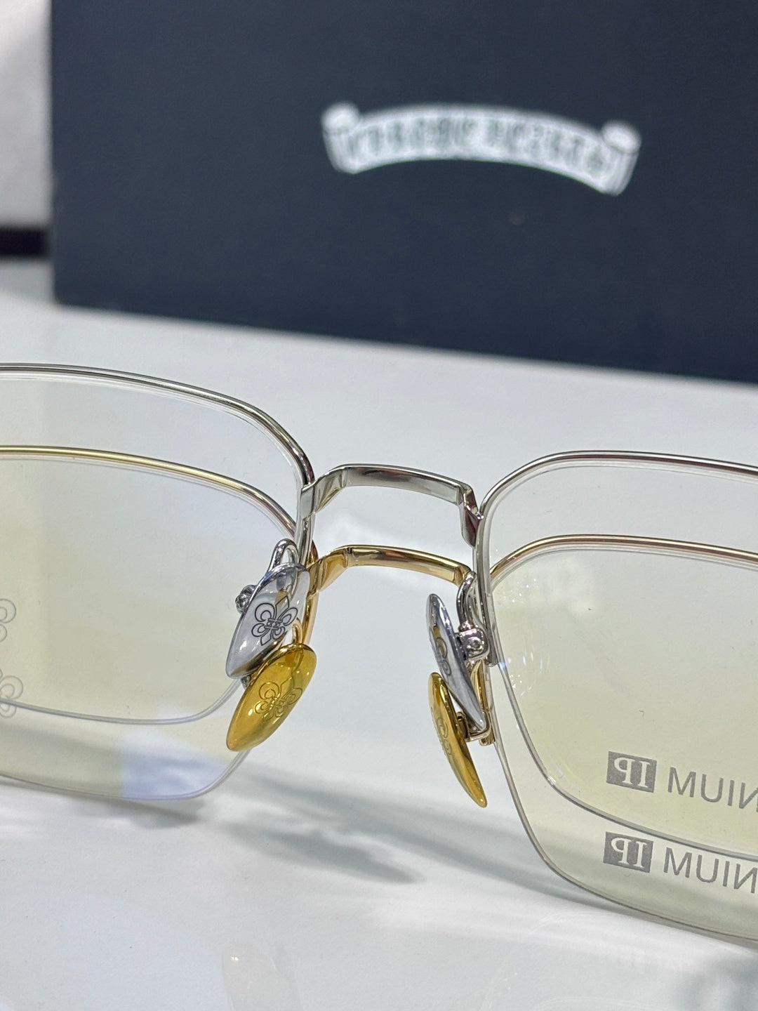 Front view of gold and silver eyeglass frames with clear lenses and amber temple tips
