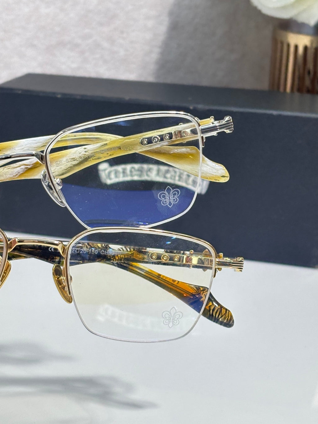 Gold-tone eyeglass frames with clear lenses, close side view with engraved accents
