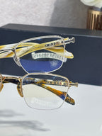 Gold-tone eyeglass frames with clear lenses, close side view with engraved accents