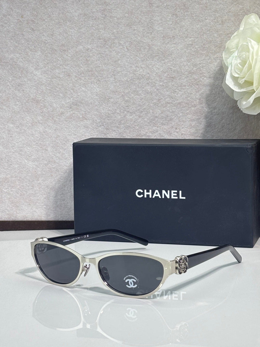 Chanel sunglasses, black frames with dark lenses, medallion emblem on temple