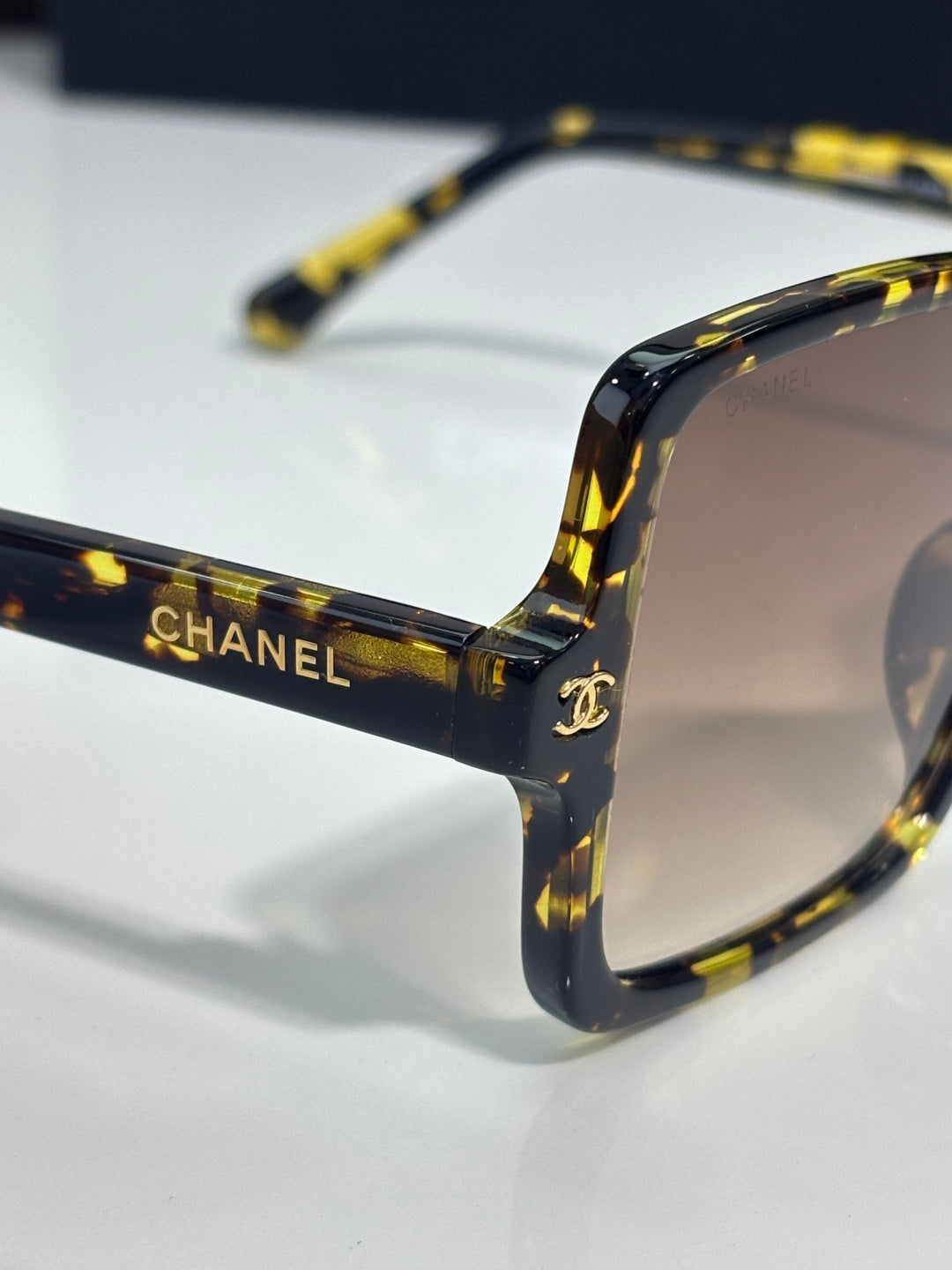 Chanel sunglasses close-up with dark tortoiseshell temples and dark lens