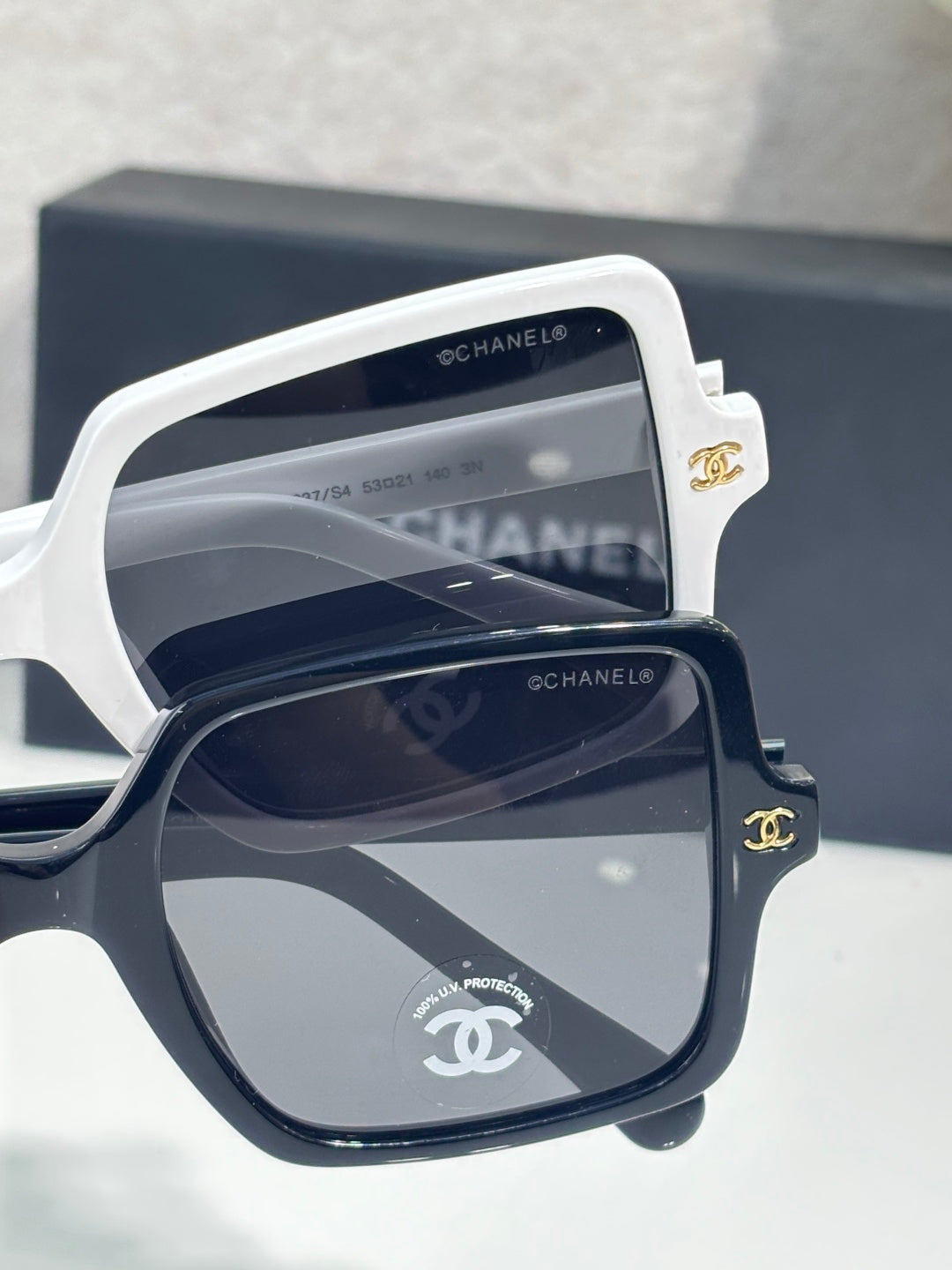 Chanel sunglasses with white frames and dark gray mirrored lenses