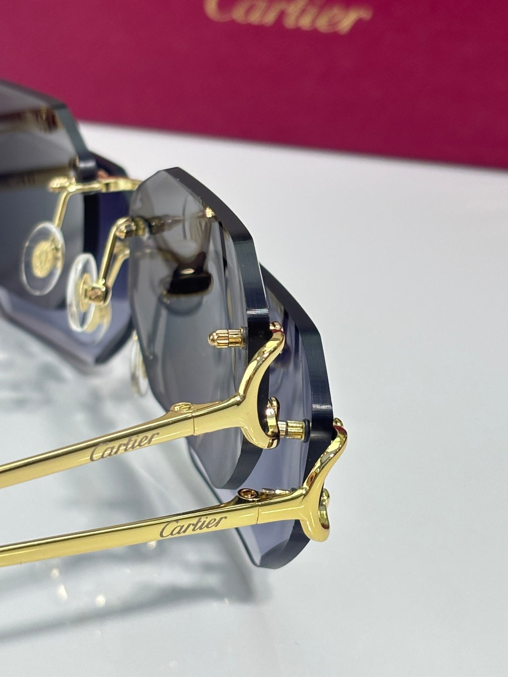 Close-up of Cartier sunglasses showing gold-tone hinges and dark tinted lenses