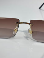 Gold-tone eyeglasses with round gold logo details at the temples and gradient lenses