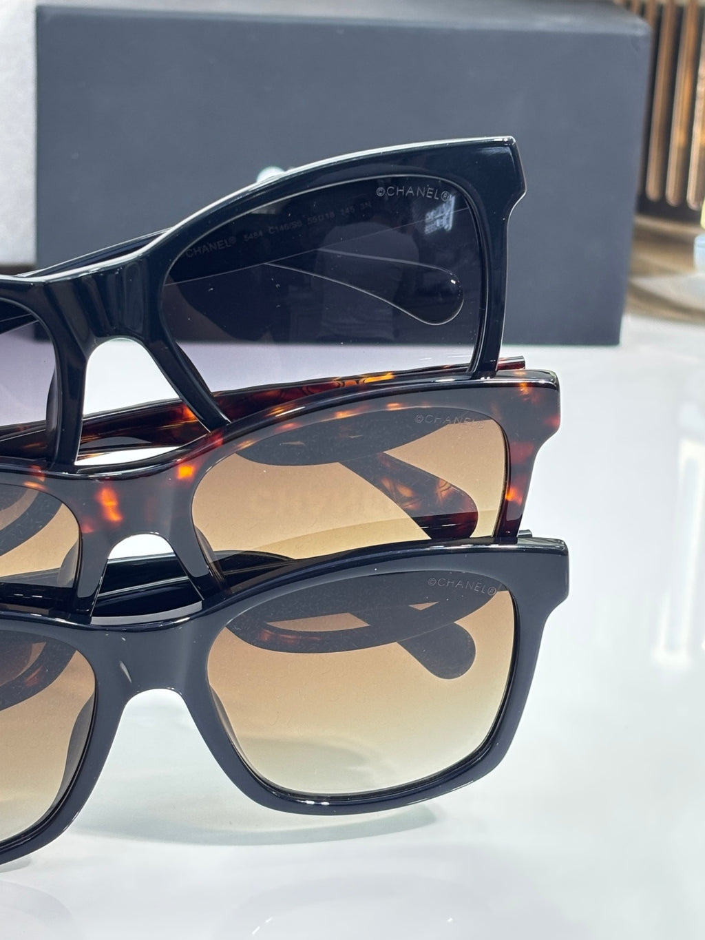 Black oversized sunglasses with amber-tinted lenses, curved frame, logo detail