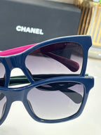 Blue square sunglasses with pink top trim and dark gradient lenses, close-up view