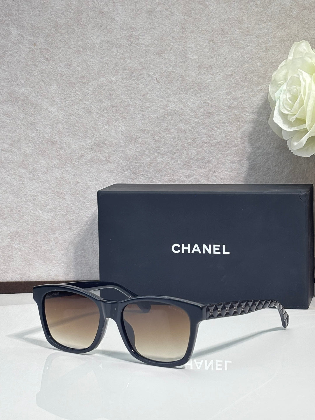 Black square sunglasses with textured temple, tinted lenses, subtle logo on frame