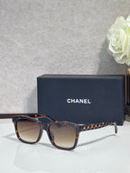 Tortoiseshell square sunglasses with dark gradient lenses, gold studded temple details