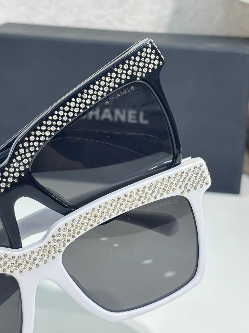 Chanel sunglasses with white frame and dark lens, edged with silver rhinestones