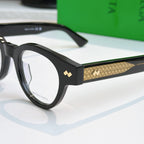 Black acetate eyeglasses with gold textured temple panel and metal logo stud