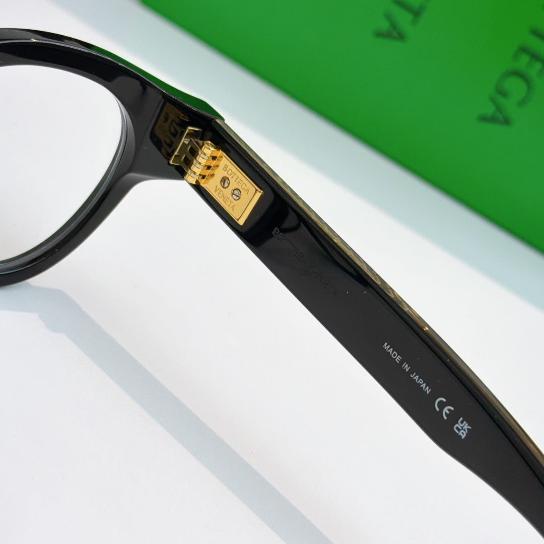 Black acetate eyeglasses close-up of gold logo plate on temple