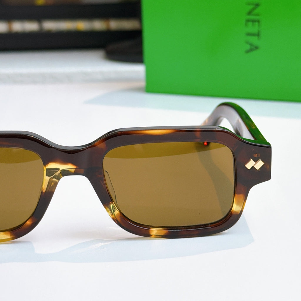 Bottega Veneta sunglasses close-up, dark frames with gold temple detail