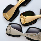 YSL sunglasses close-up showing black and cream frames with gold logo temple details.
