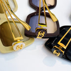 Sunglasses close-up with gold-tone logo hardware and tinted lenses