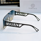 Black sunglasses with clear lenses, gold hardware, and Versace logo arms