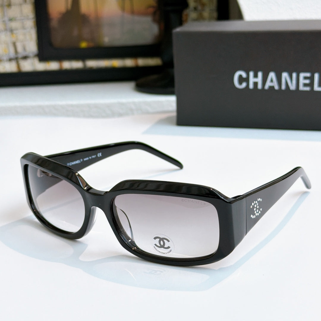 Black cat-eye glasses with light gray tinted lenses and side logo detail