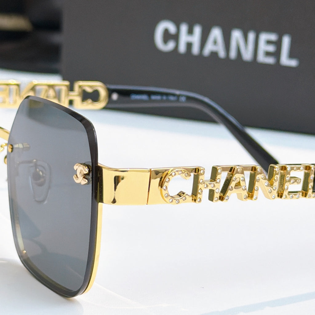 Chanel sunglasses close-up, gold logo temple and dark lenses on black frame