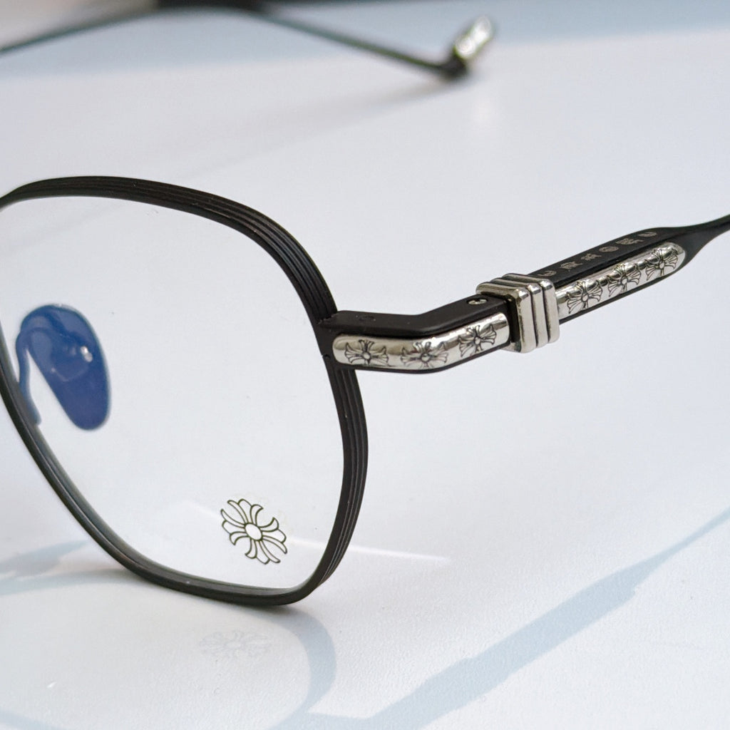 Close-up of round eyeglass frame: black front with blue lens and silver patterned temple