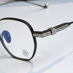 Close-up of round eyeglass frame: black front with blue lens and silver patterned temple
