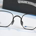 Round black eyeglasses with blue-tinted lens panels and small side emblem