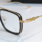 Close-up of gold eyeglass frame with decorative temple and clear lens