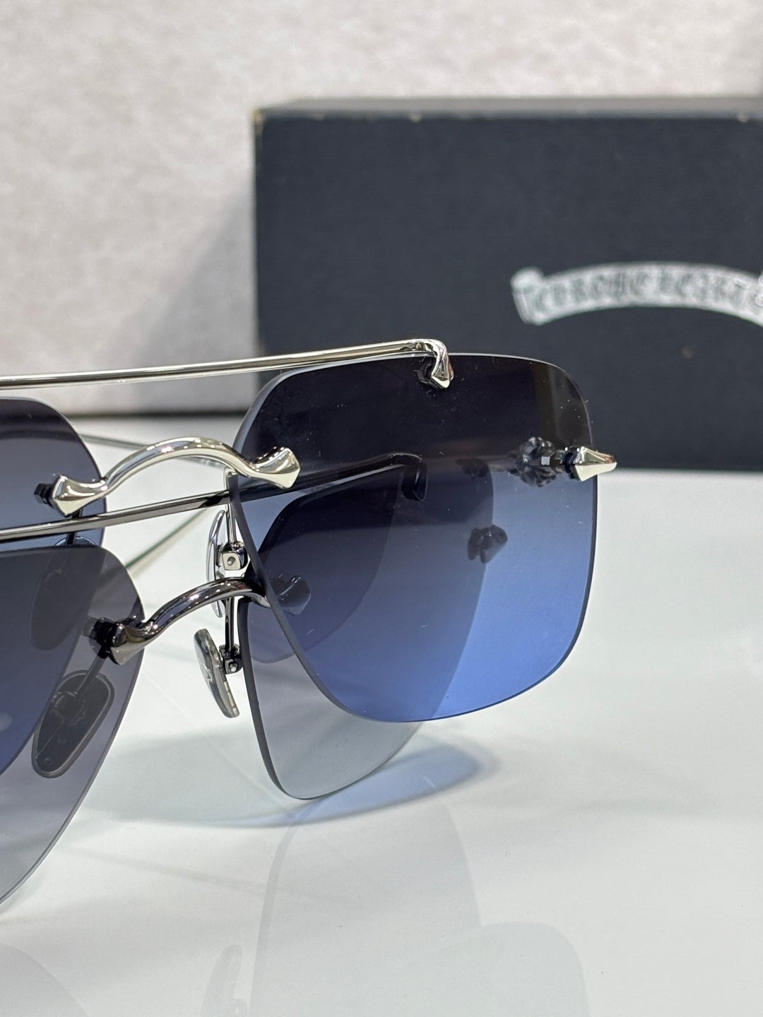 Chrome glasses close-up with navy lenses and silver frame, temple detail